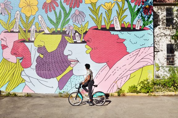 Homme en vélo devant une murale à Montréal