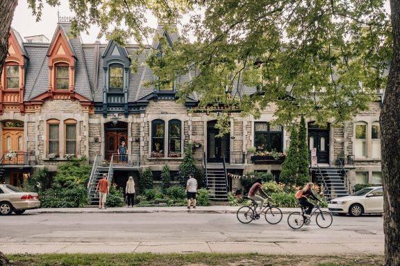 Des personnes qui font du vélo devant les maisons du Carré St-Louis à Montréal
