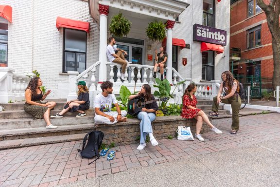 Plusieurs personnes devant l'auberge Saintlo Montréal qui parlent entre eux.