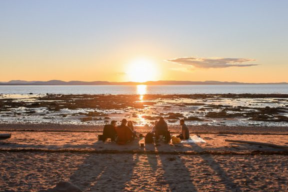 Groupe de personnes sur la plage au couché de soleil