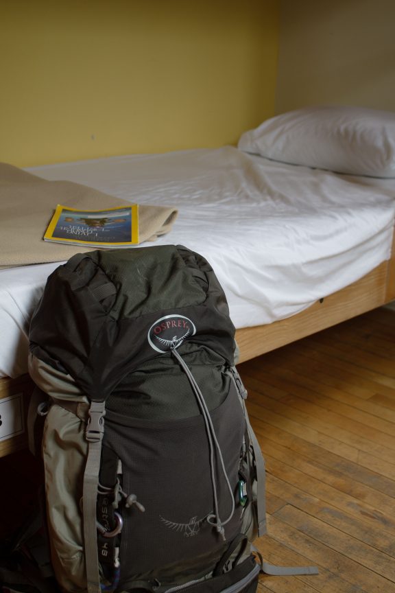 Un lit dans un dortoir, avec un sac de voyageur