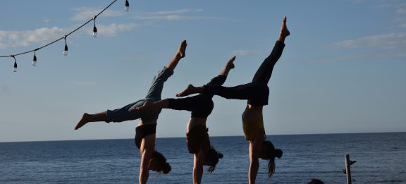Circus artists walking on their hands in front of the sea