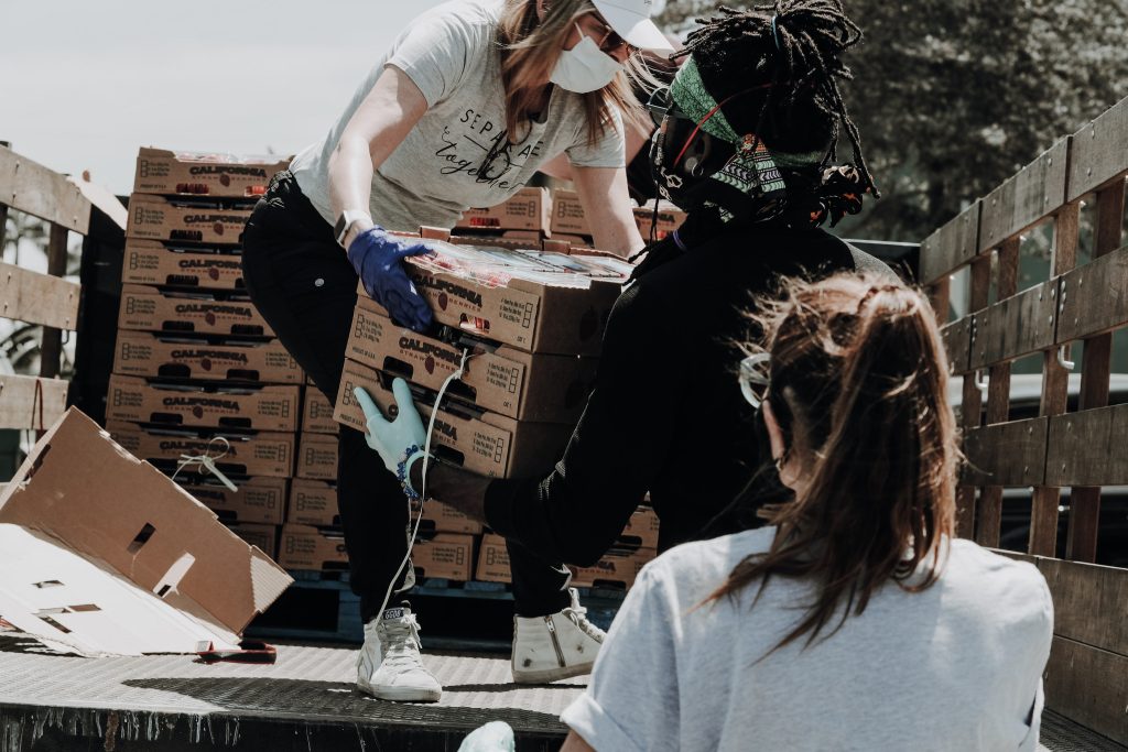 Deux personnes s'aident à descendre des caisse de nourriture d'un camion