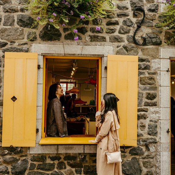 Two people on the windowsill of a brick building