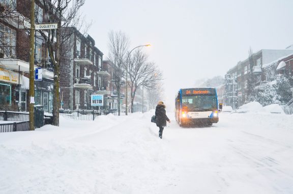 Une personne qui attend l'autobus dans la neige à Montréal