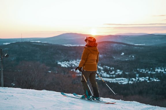 Femme en ski devant un coucher de soleil