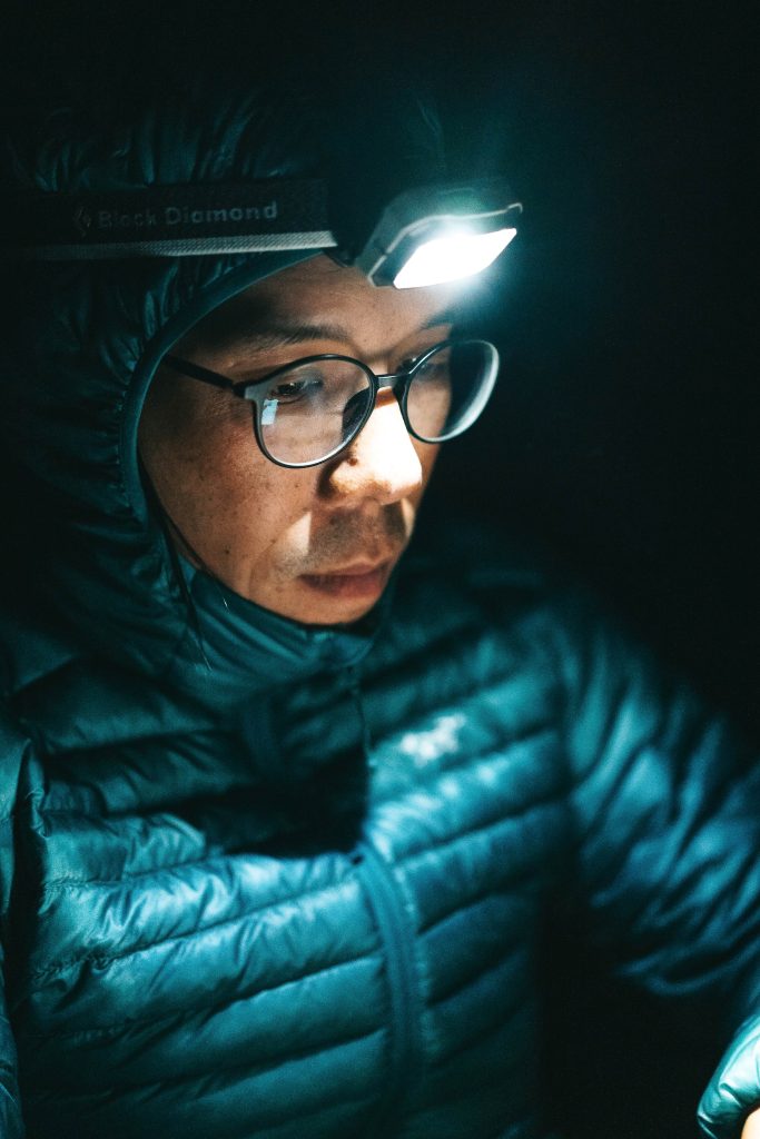 Woman wearing a headlamp at night with a coat on