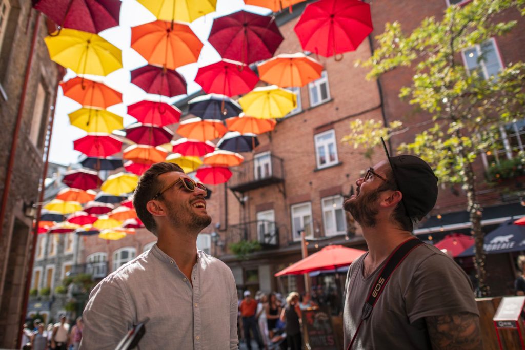 Deux personnes qui regarde des parapluies colorés suspendus