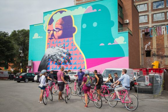 Tour à vélo devant une murale à Montréal