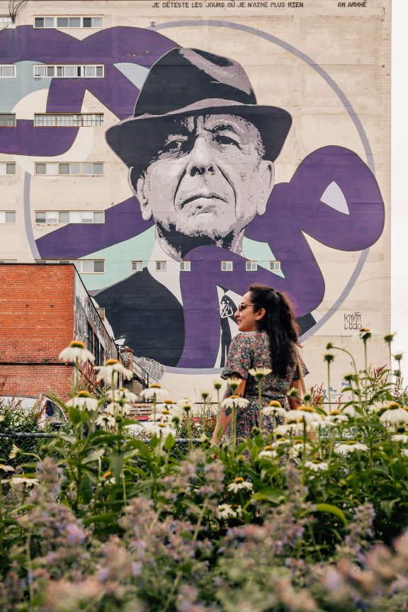 A person in front of Leonard Cohen's mural