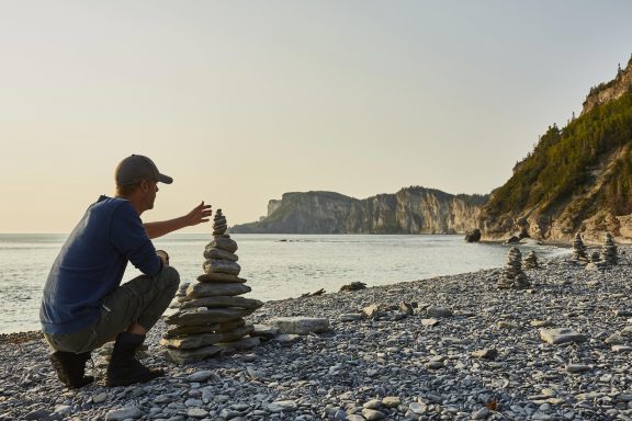 Homme qui empile des roches au cap Bon-Ami, Parc Forillon