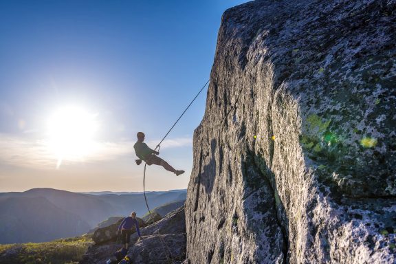 Personne suspendue à une corde d'escalade avec une vue imprenable à l'arrière