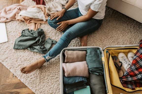 A person packing, sitting on the floor