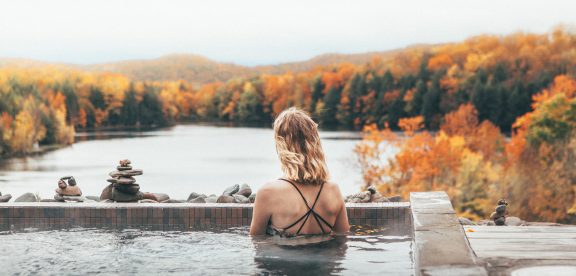 Femme dans une piscine devant une forêt et un lac en automne