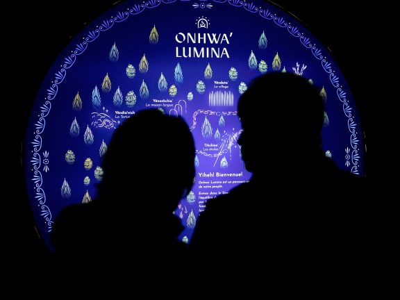 Two silhouettes in front of an information panel about Onhwa' Lumina