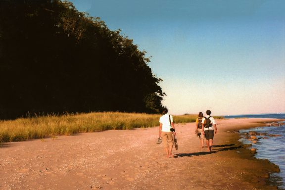 Three people walking along a beach