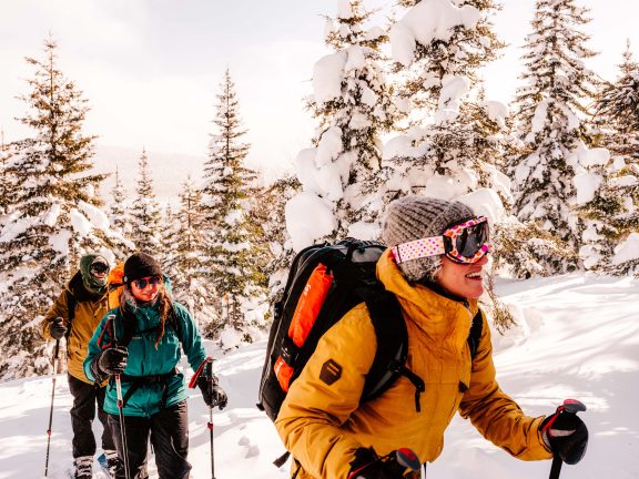 Personnes montant une montagne en ski, dans un paysage enneigé.